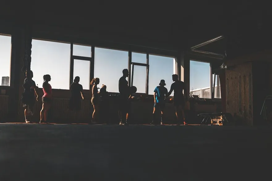 Silhouetten van sportende mensen voor grote ramen in een sportzaal