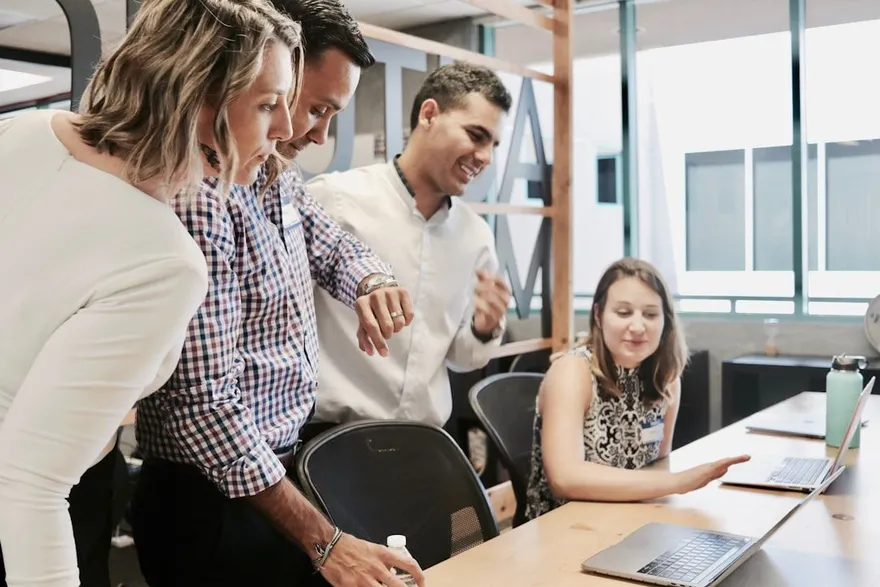 Collega's kijken samen mee op een laptop tijdens een werkoverleg